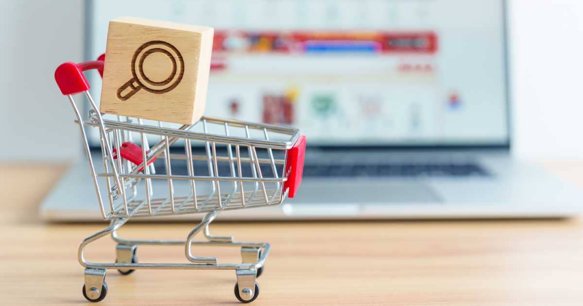 Differences Between Organic Search Results And Paid Search Results | Shopping cart with Magnifying icon block and laptop computer